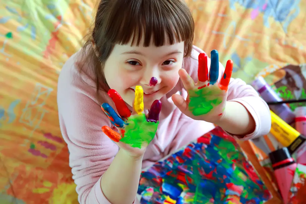 Lachendes Mädchen mit bunter Fingerfarbe an den Händen